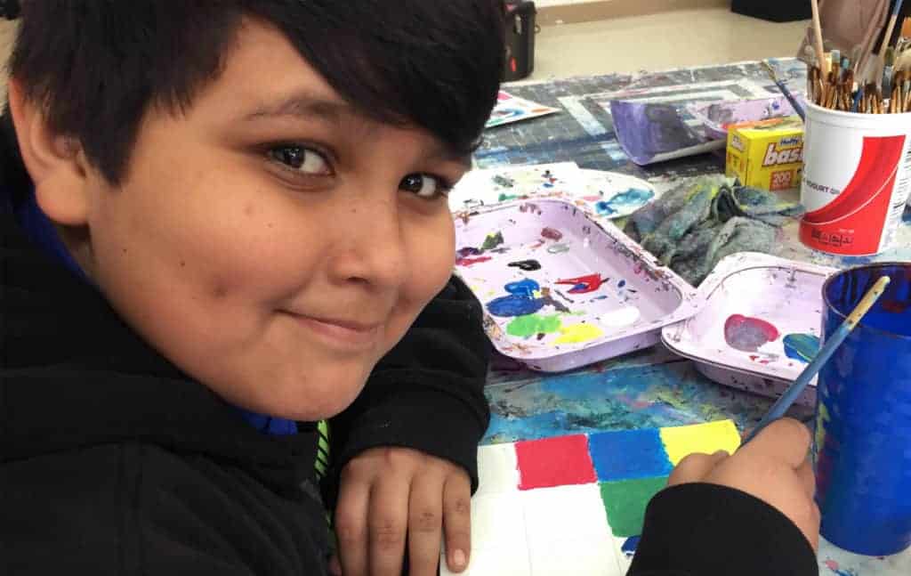 A young CCATE student smiling during painting class