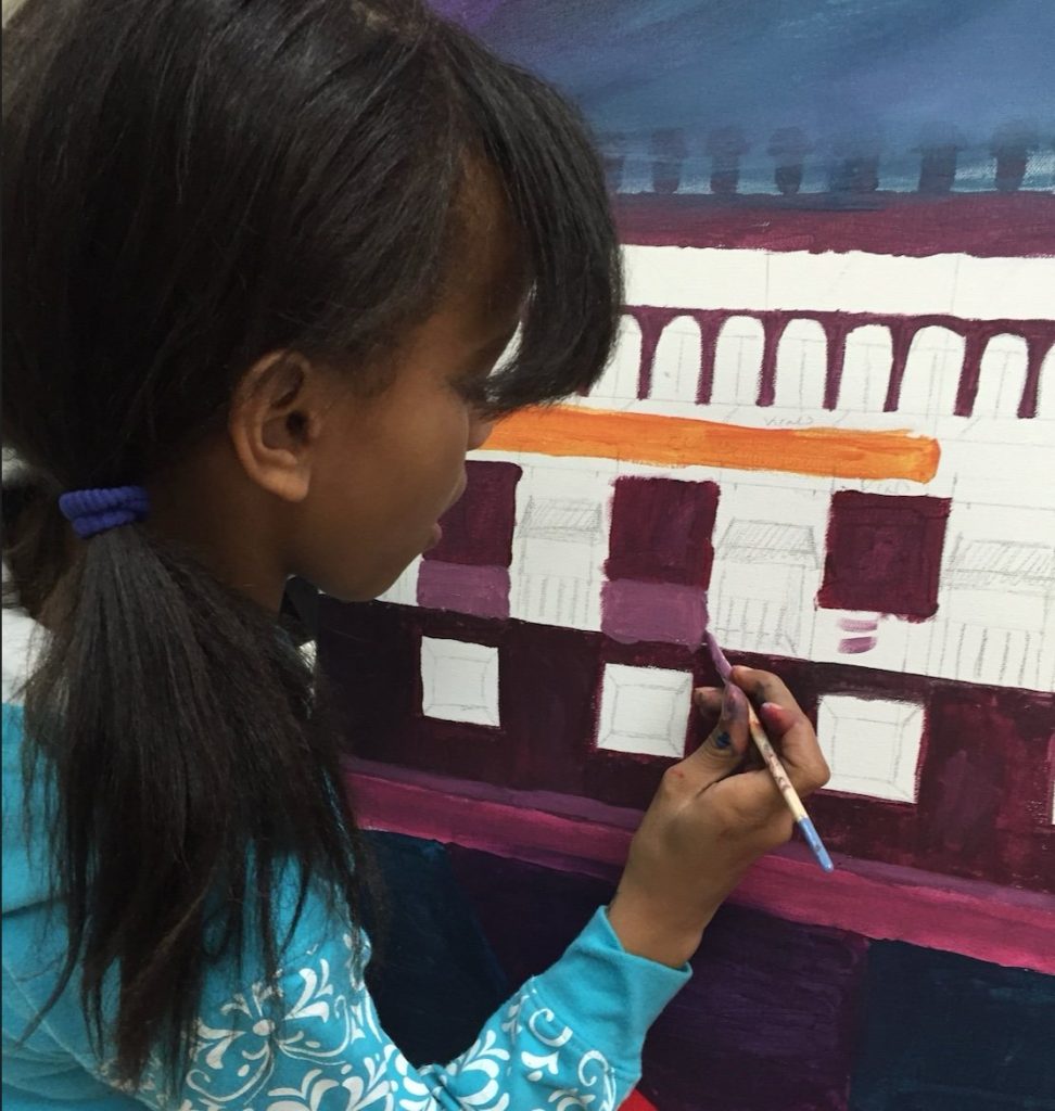 A young painter adding color to the mural The history of Mexico