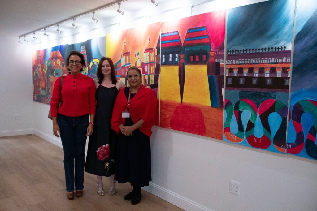Three women standing in front of the lit murals