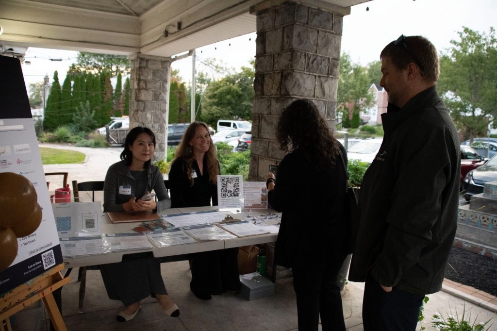 Two CCATE team members welcoming guests at a table on the stone porch