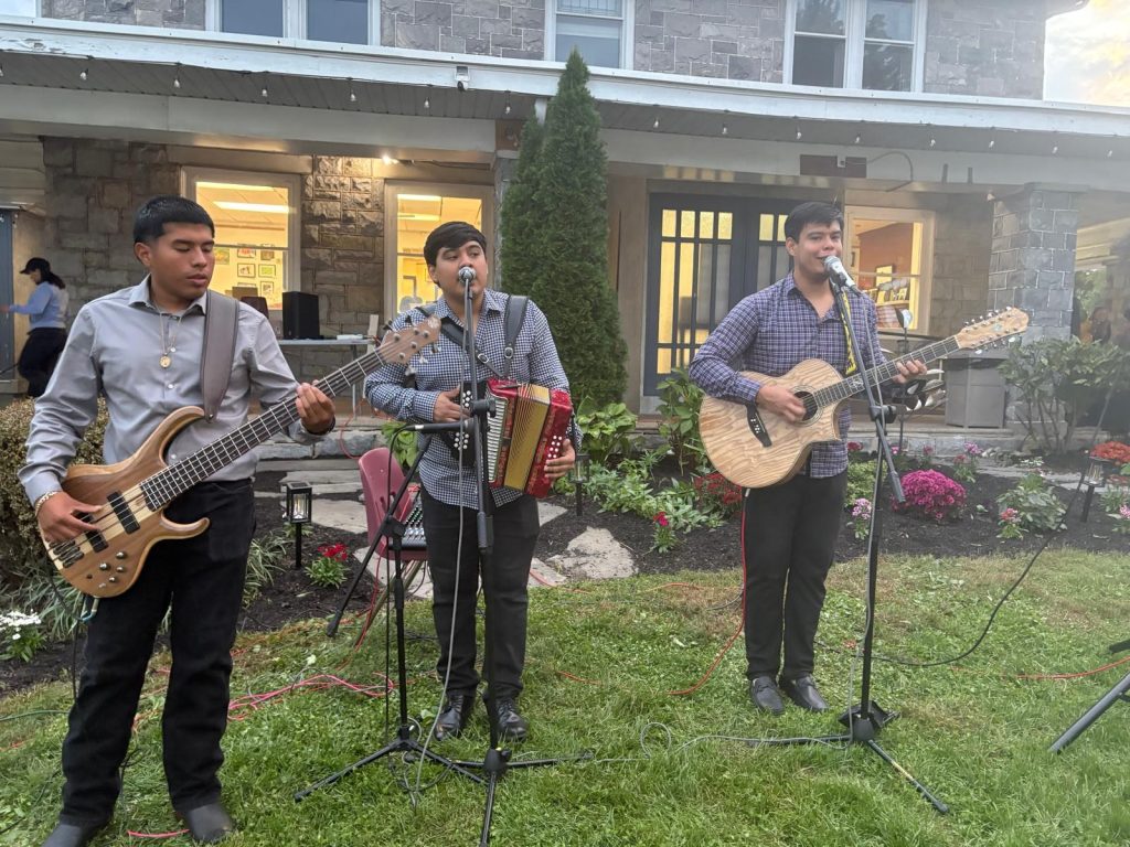 Nuevo Reyes playing bass, accordion and guitar on the lawn in front of CCATE